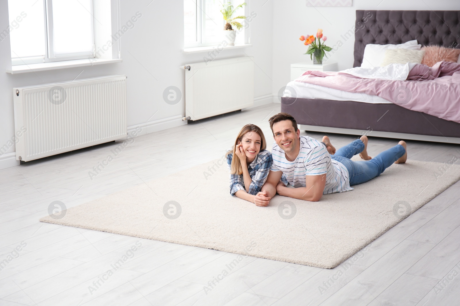 Photo of Lovely young couple lying on cozy carpet at home