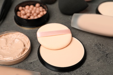 Composition with skin foundation, powder and beauty accessories on grey background
