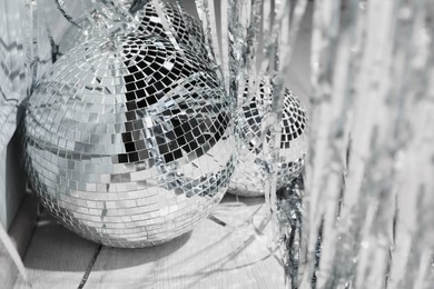 Shiny disco balls and foil fringe curtain indoors, closeup