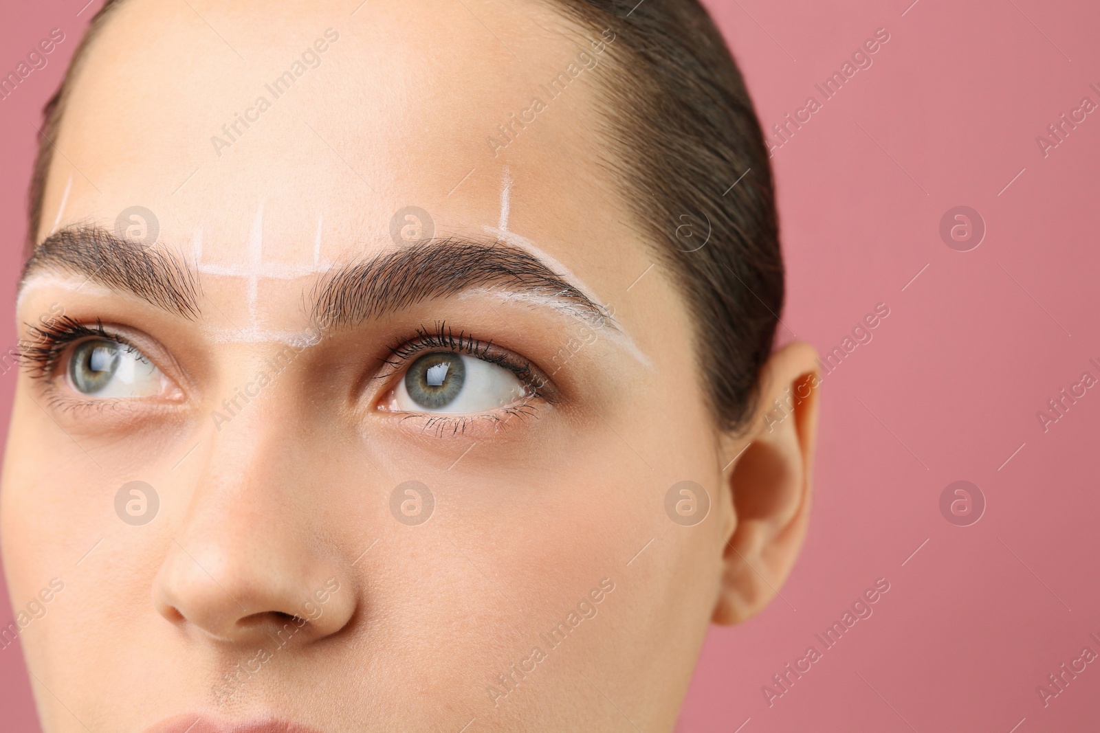 Photo of Eyebrow correction. Young woman with markings on face against pink background, closeup. Space for text