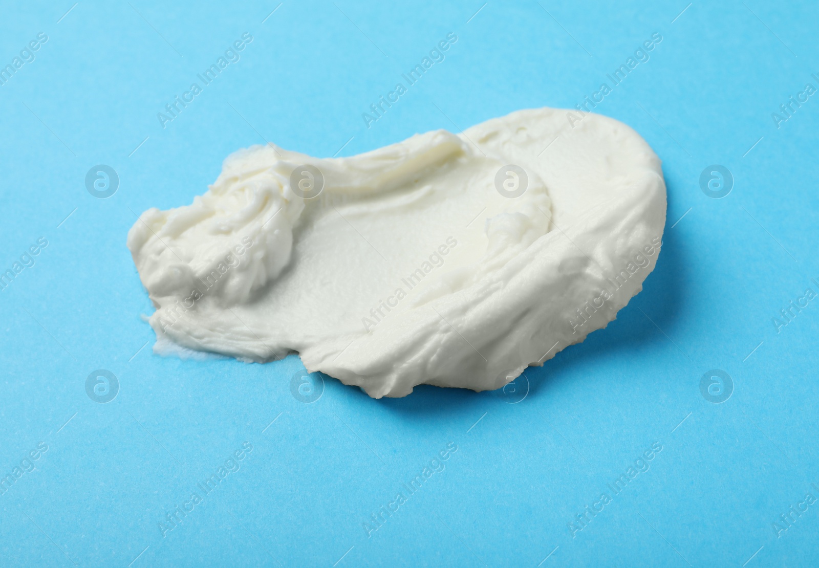 Photo of Smear of delicious cream cheese on light blue background