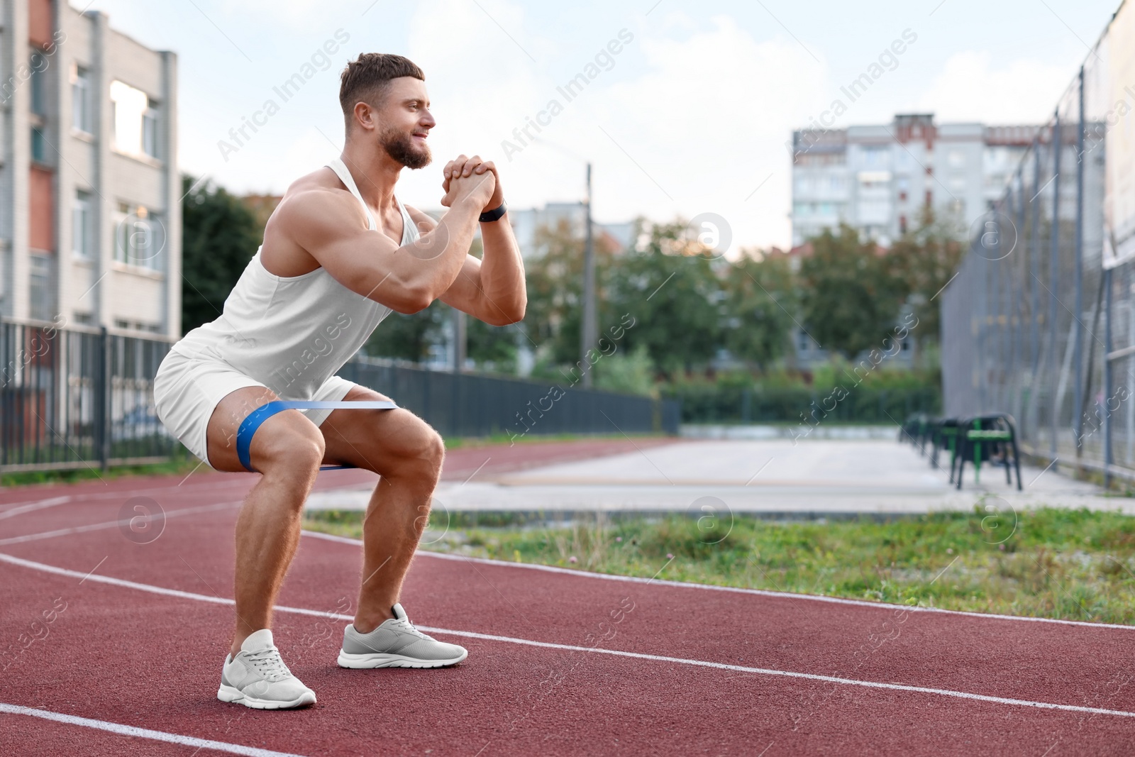 Photo of Muscular man doing exercise with elastic resistance band at stadium