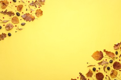 Autumn composition with dry leaves and cones on yellow background, flat lay. Space for text