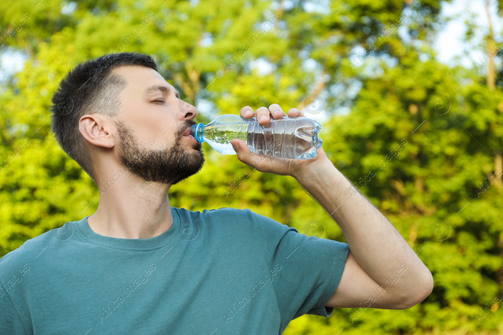 Photo of Man drinking water outdoors on hot summer day. Refreshing drink
