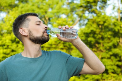 Man drinking water outdoors on hot summer day. Refreshing drink