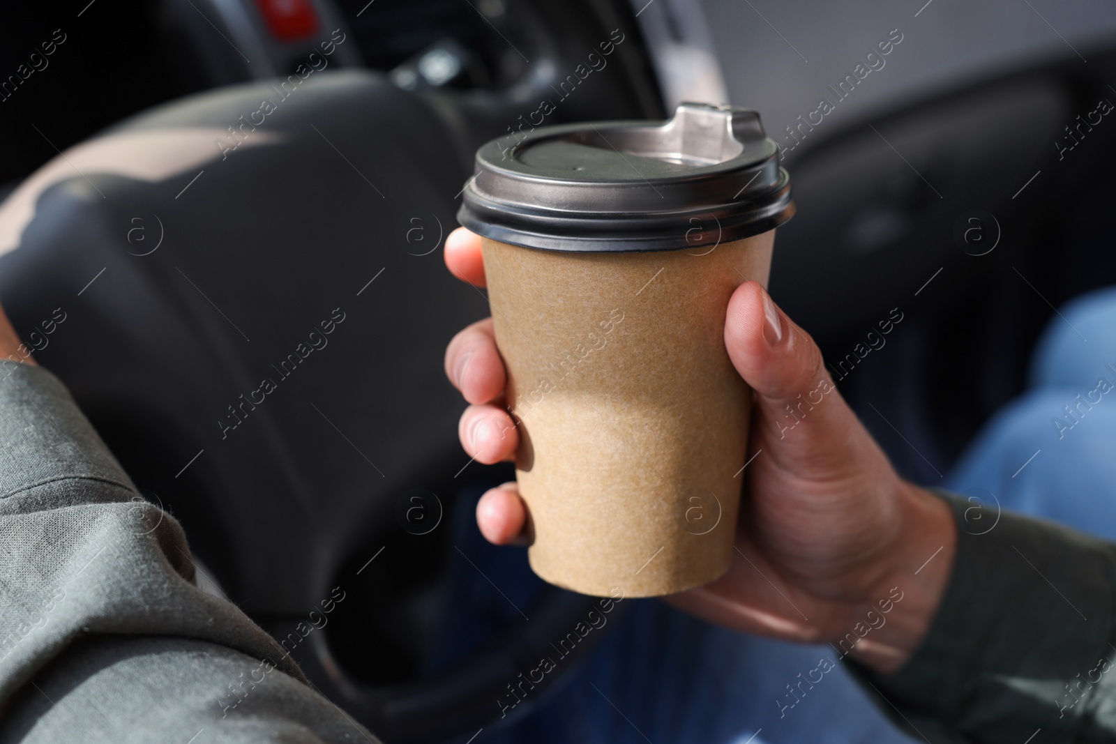 Photo of Coffee to go. Man with paper cup of drink driving his car, closeup