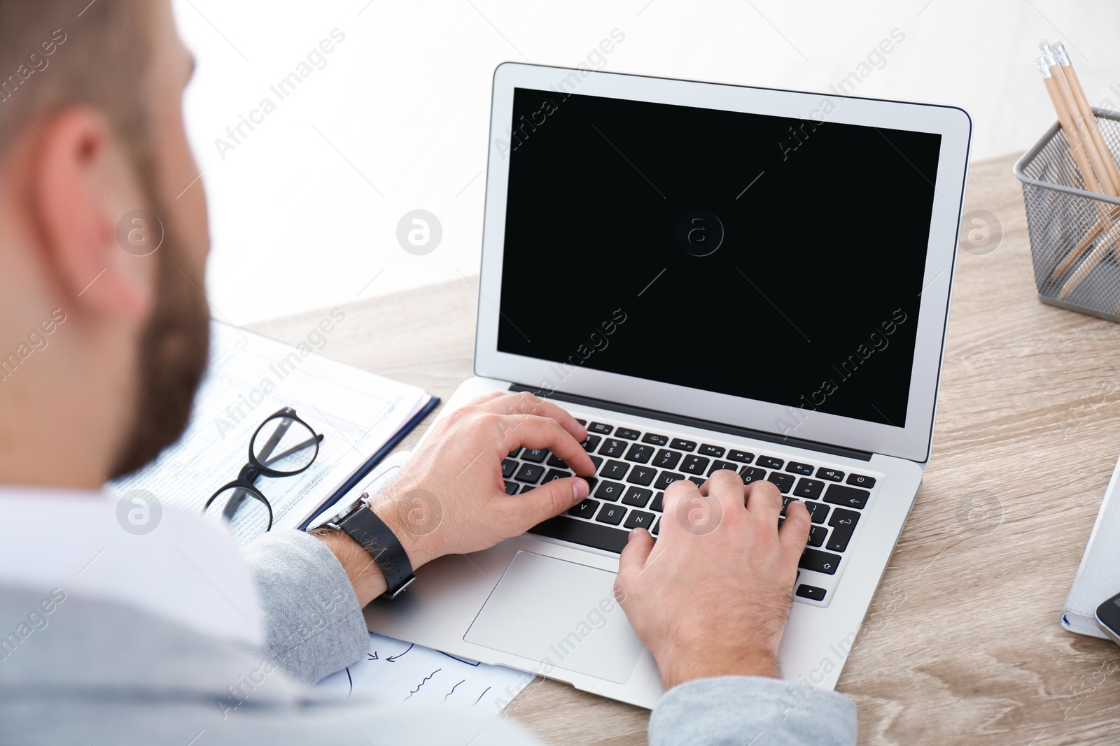 Photo of Young man working with laptop at table, closeup