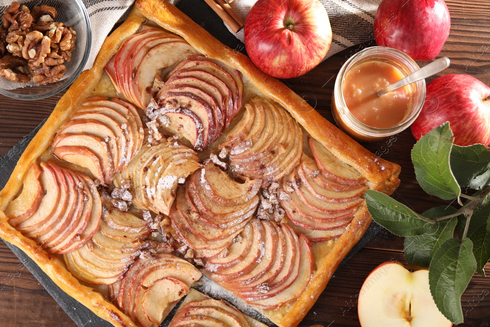 Photo of Freshly baked apple pie and ingredients on wooden table, flat lay