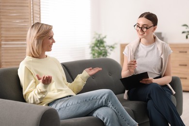 Photo of Professional psychotherapist working with on sofa patient in office