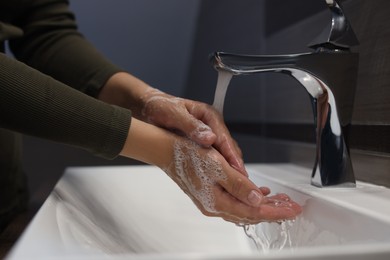 Photo of Woman washing hands in bathroom, closeup view