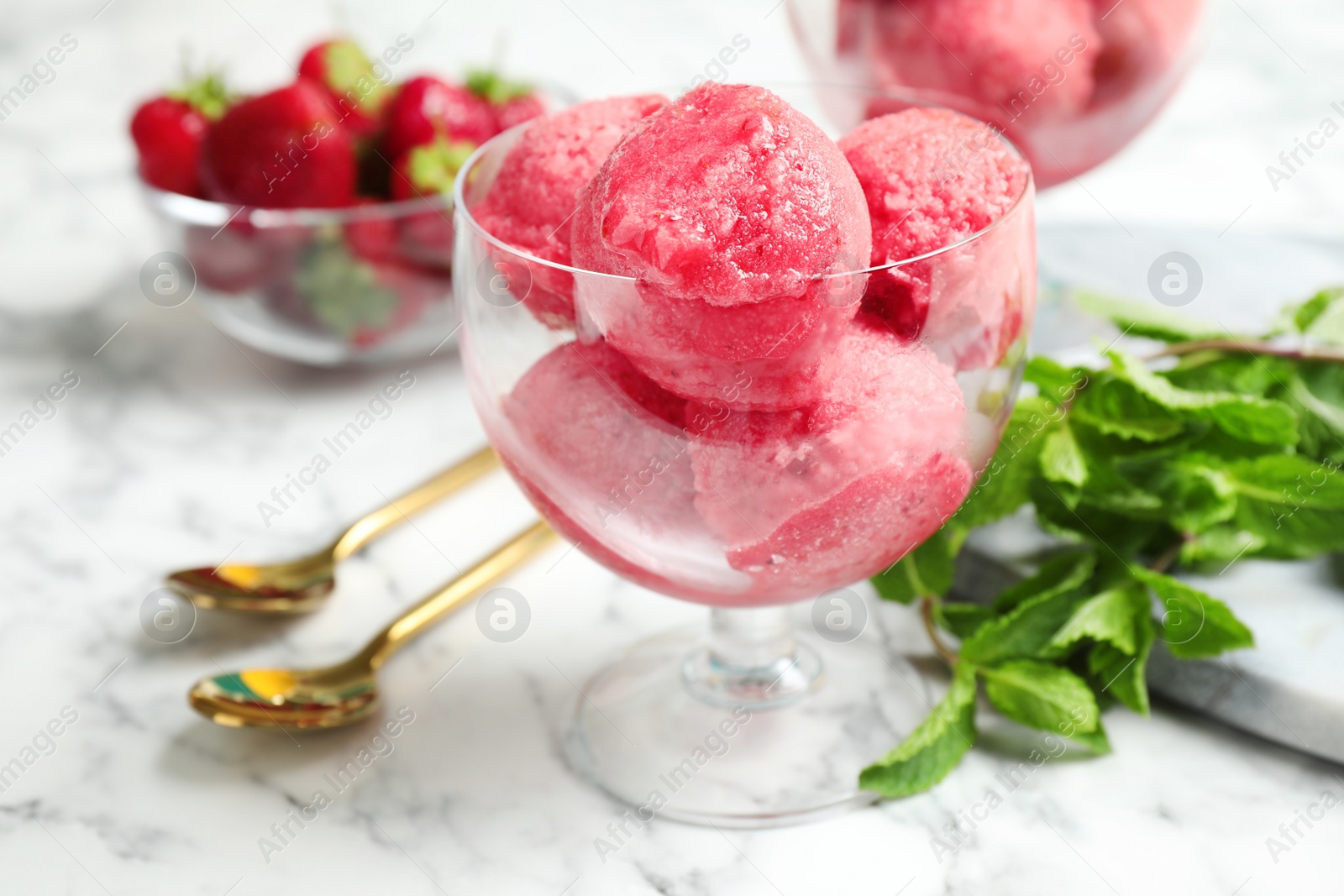 Photo of Delicious pink ice cream served in dessert bowl on marble table