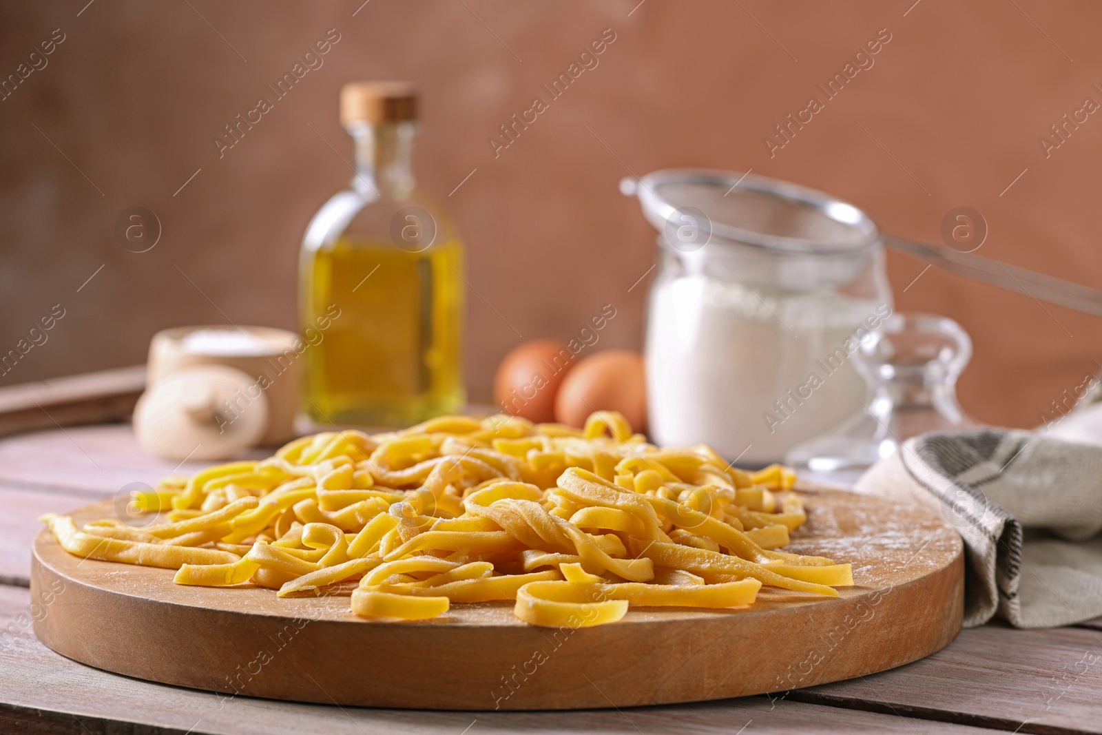 Photo of Board with homemade pasta on wooden table