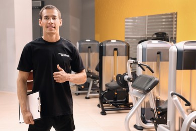 Portrait of personal trainer with clipboard in modern gym
