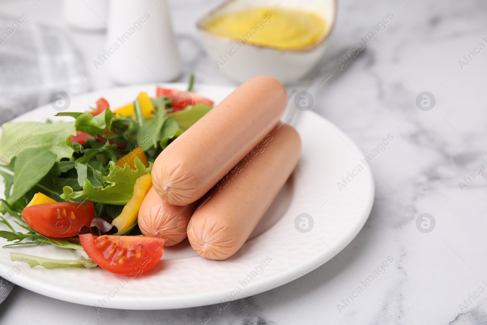 Photo of Delicious boiled sausages with salad on white marble table