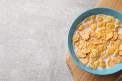 Photo of Bowl with tasty cornflakes and milk on light grey table, top view. Space for text