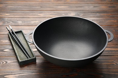 Empty iron wok and chopsticks on wooden table