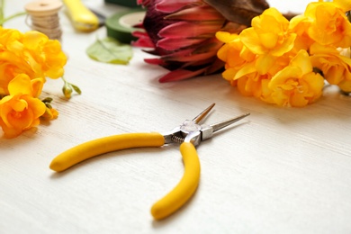 Photo of Florist workplace with pliers and flowers on table