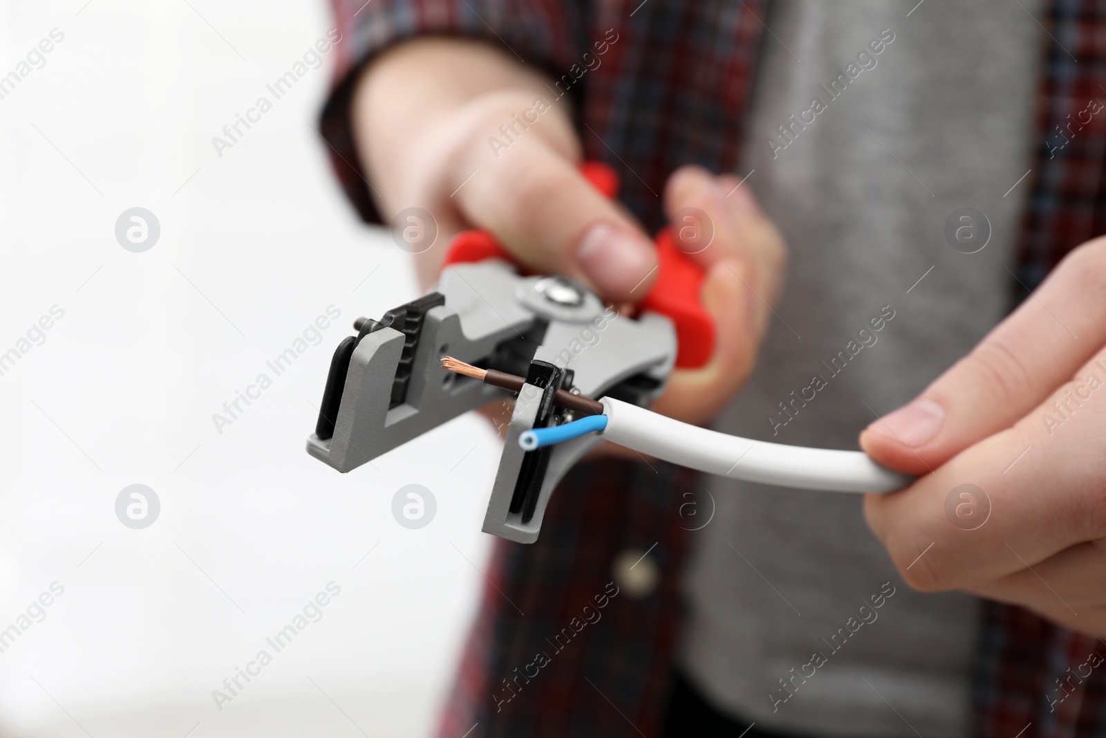 Photo of Professional electrician stripping wiring on white background, closeup