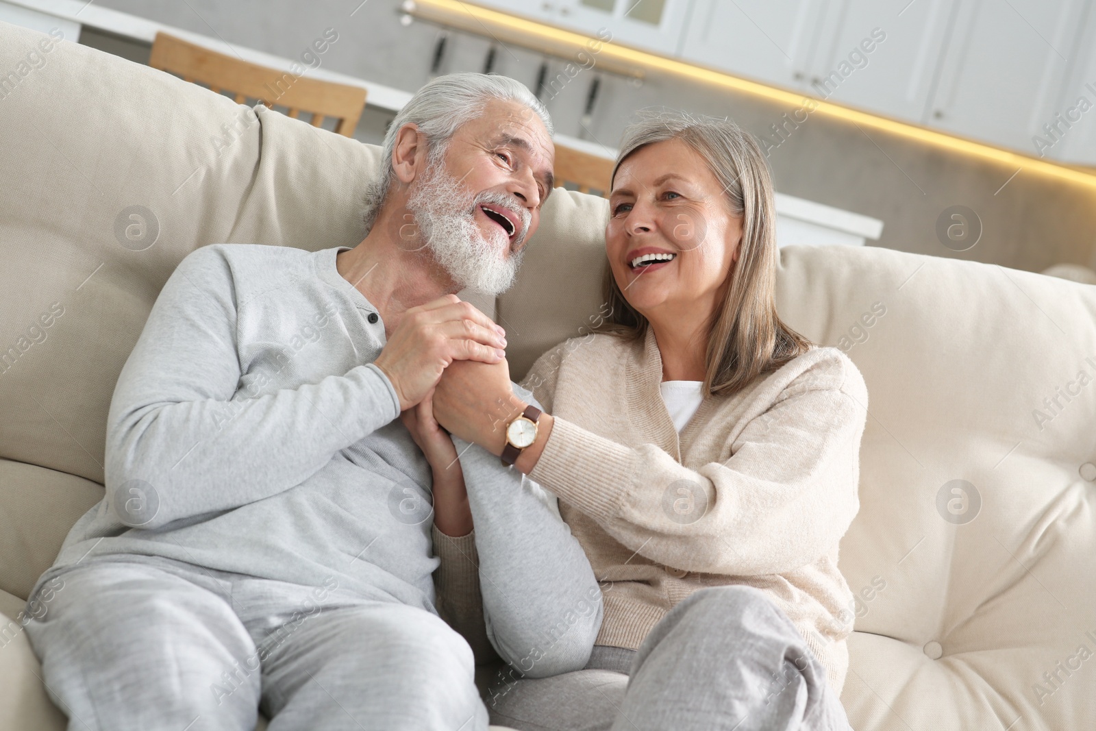 Photo of Affectionate senior couple relaxing on sofa at home