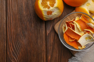 Dry peels and oranges on wooden table, flat lay. Space for text