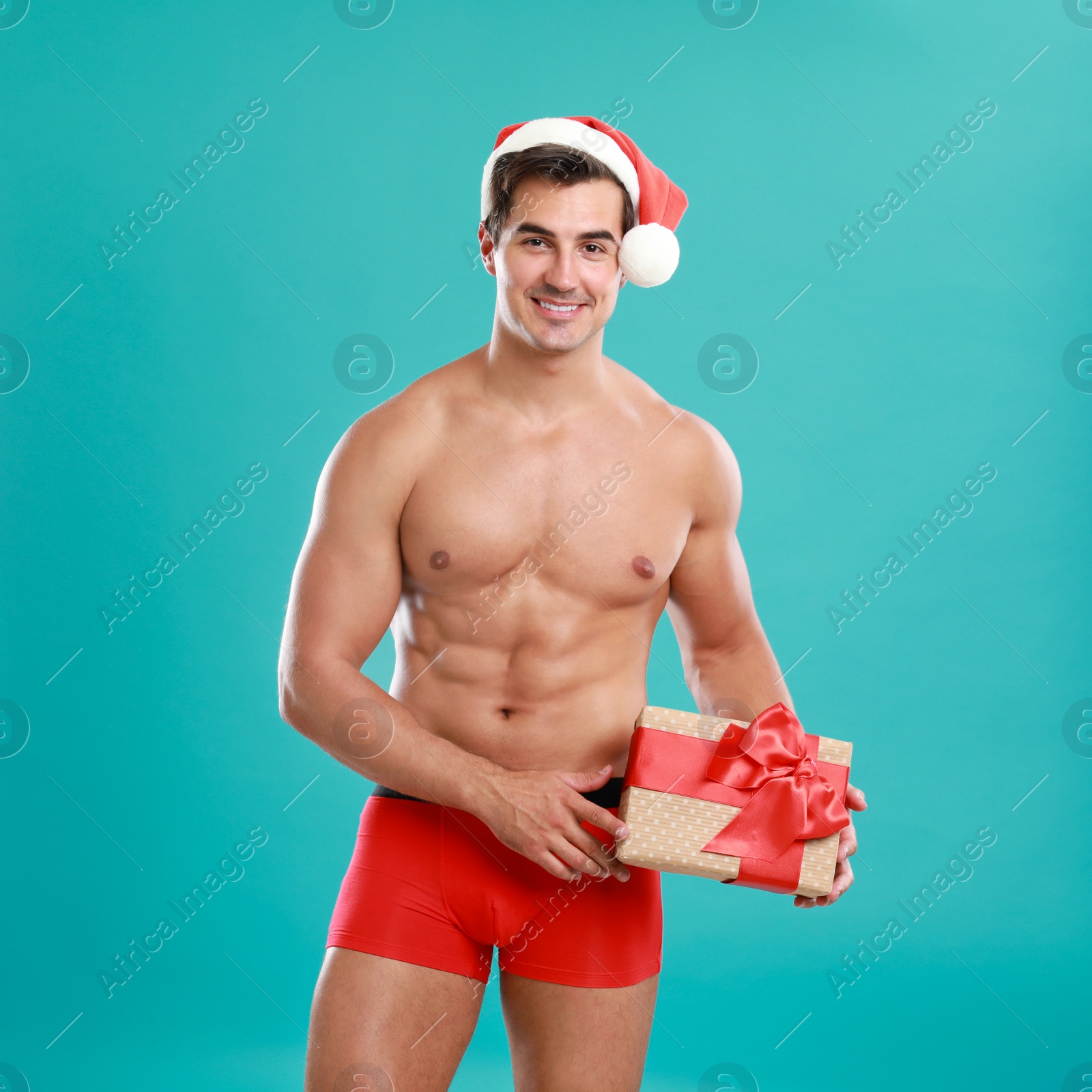 Photo of Sexy shirtless Santa Claus with gift on blue background