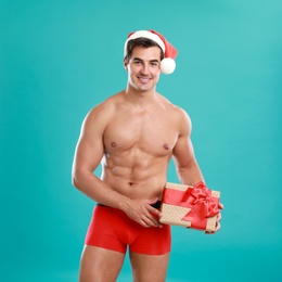 Sexy shirtless Santa Claus with gift on blue background