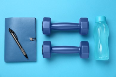 Flat lay composition with dumbbells on light blue background