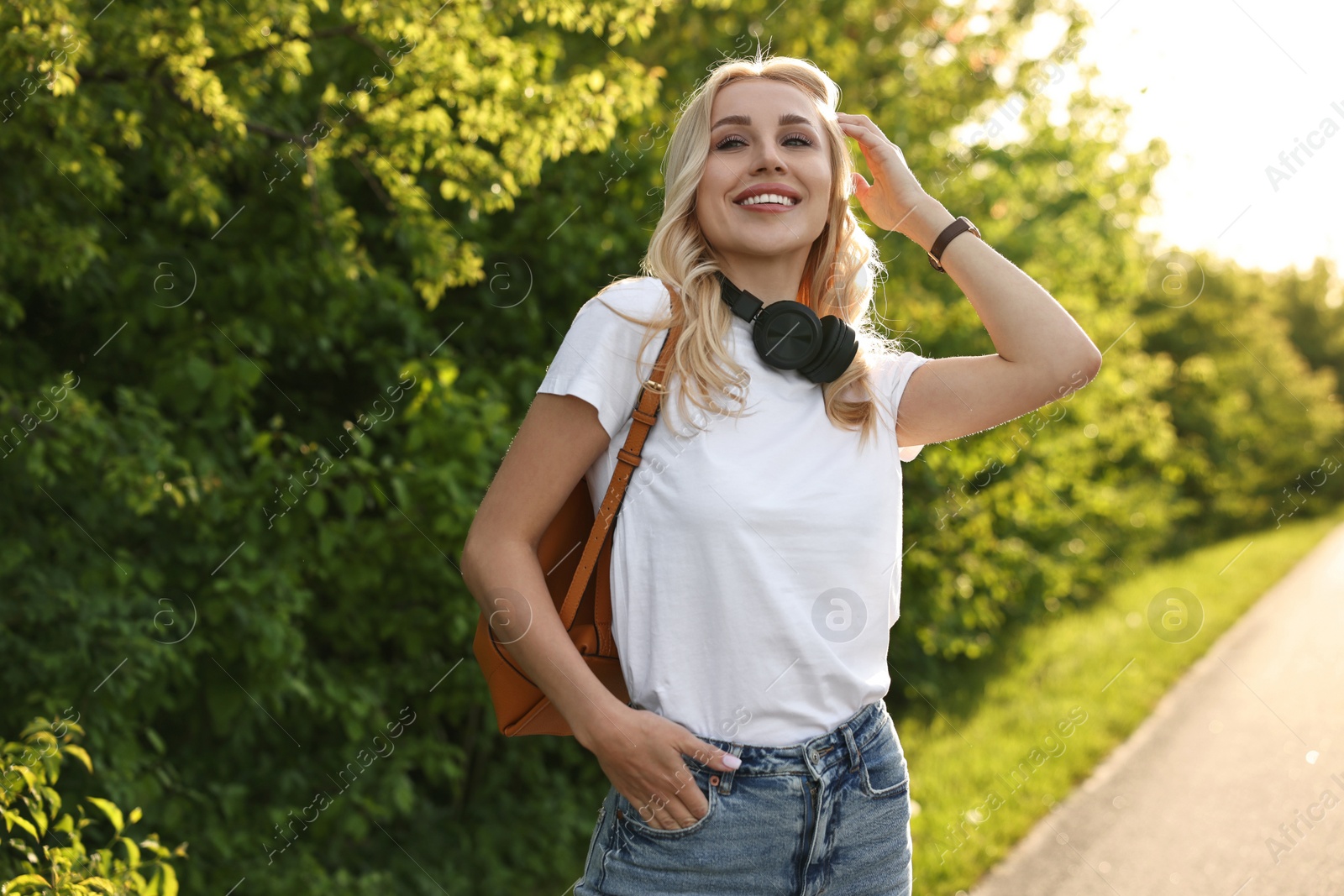 Photo of Happy young woman with headphones in park on spring day