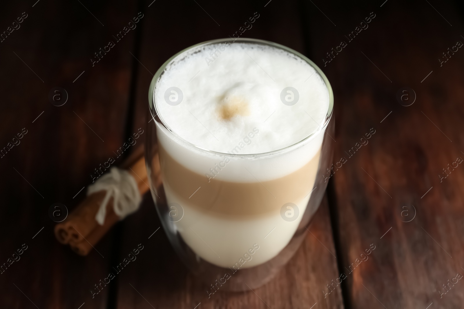 Photo of Delicious latte macchiato and cinnamon on wooden table