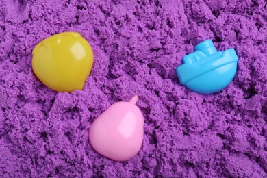 Photo of Toys on violet kinetic sand, flat lay