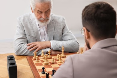 Photo of Men playing chess during tournament at table indoors