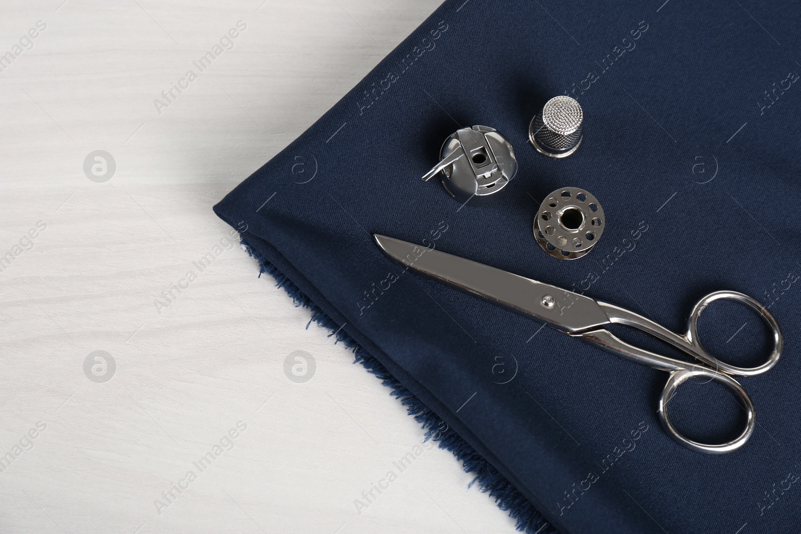 Photo of Different sewing items and fabric on light beige wooden table, above view