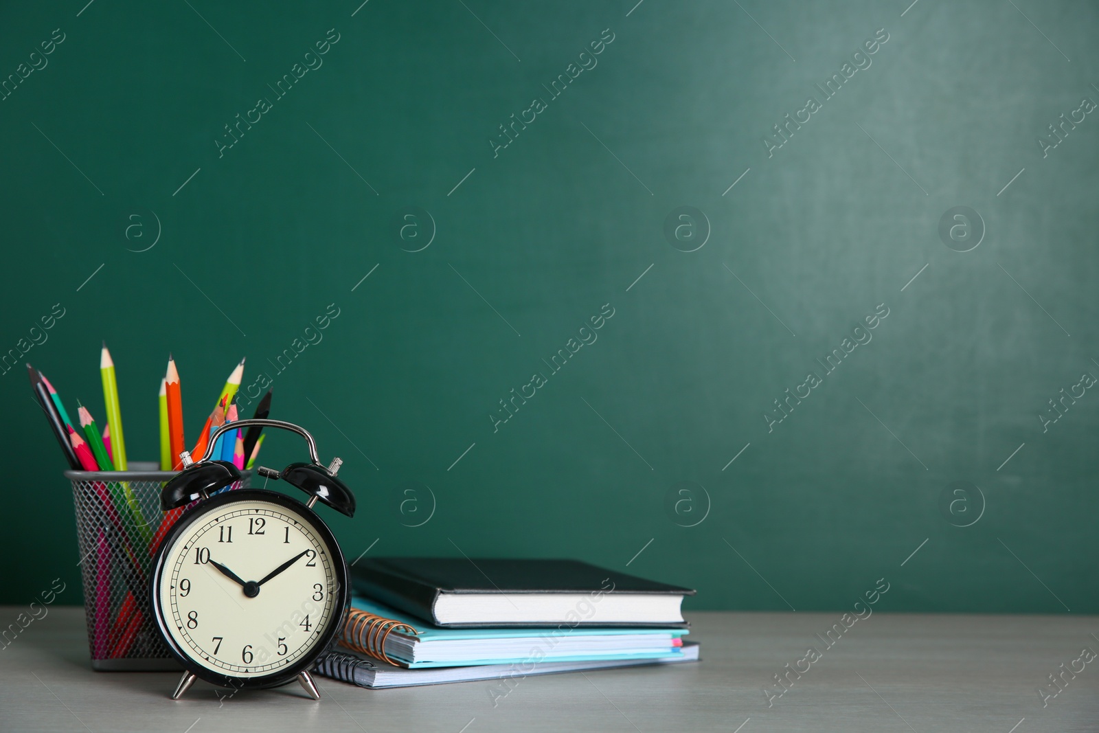 Photo of Alarm clock and school stationery on white wooden table, space for text. Doing homework