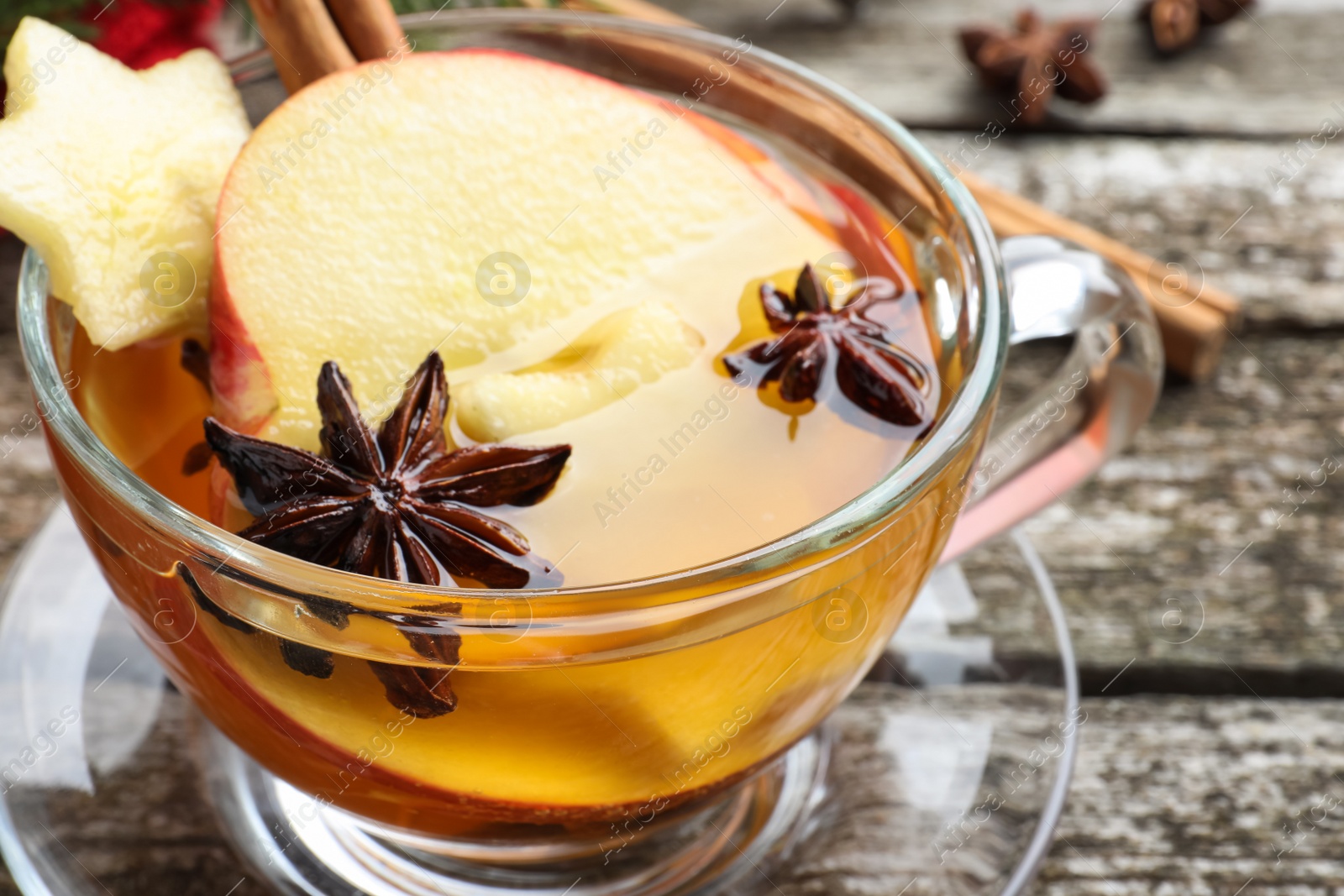 Photo of Glass cup of hot mulled cider on table, closeup