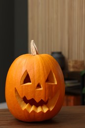 Photo of Carved pumpkin for Halloween on wooden table indoors, space for text