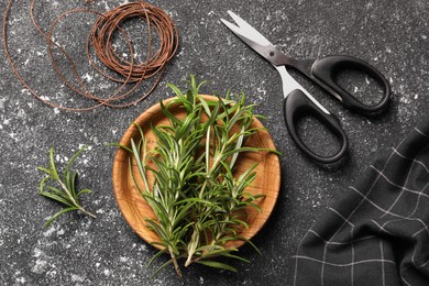 Fresh rosemary, scissors and threads on grey textured table, flat lay