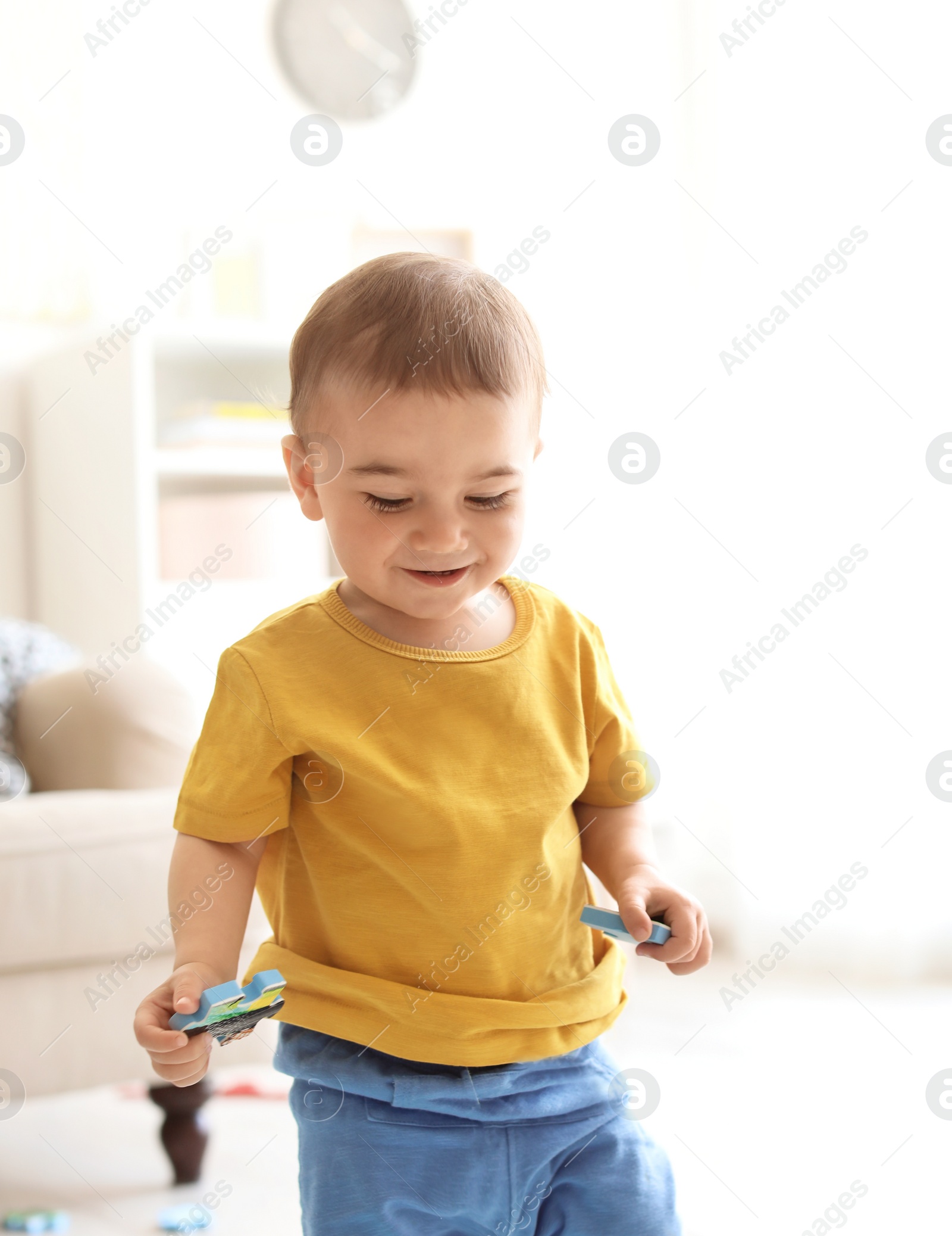 Photo of Adorable little boy playing with puzzle indoors