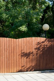 Photo of Wooden fence near trees on sunny day outdoors