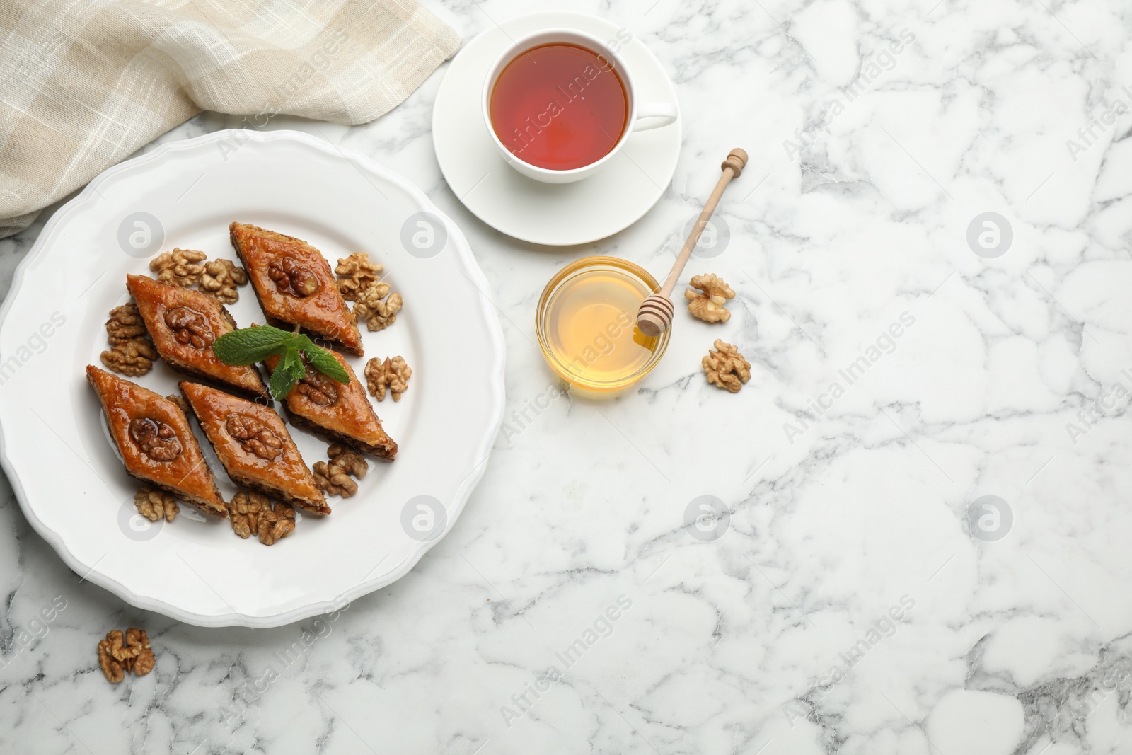 Photo of Delicious honey baklava with walnuts served on white marble table, flat lay. Space for text