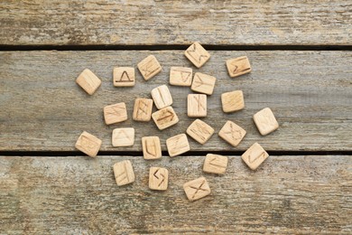 Photo of Runes with different symbols on wooden table, flat lay