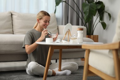 Photo of Young woman preparing face mask in front of mirror at home. Spa treatments