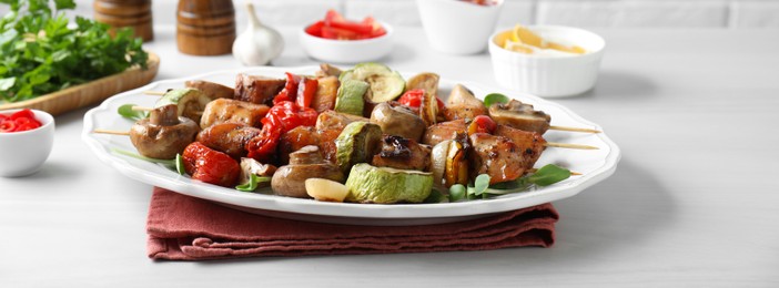 Photo of Delicious shish kebabs with vegetables and microgreens served on white table, closeup