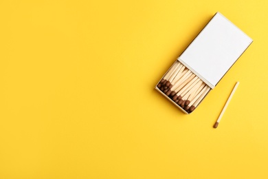 Photo of Cardboard box with matches on color background, flat lay. Space for text