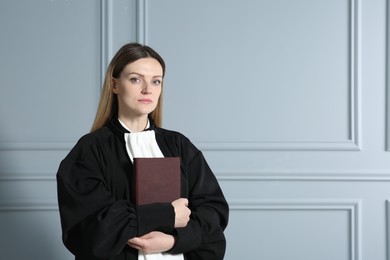Portrait of judge with book near grey wall. Space for text