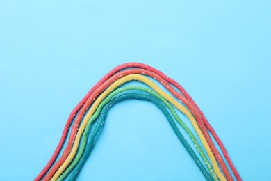 Photo of Rainbow of gummy strings on light blue background, flat lay