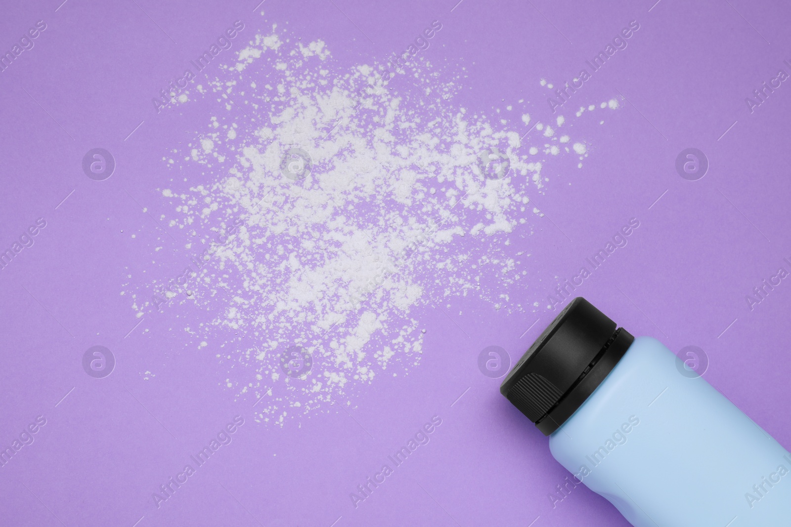 Photo of Bottle and scattered dusting powder on violet background, top view. Baby cosmetic product