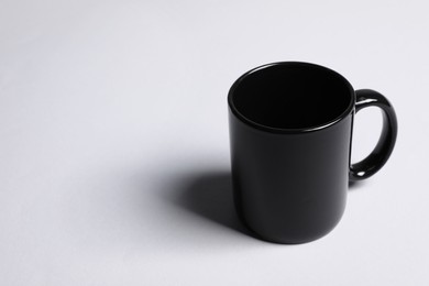 Photo of One black ceramic mug on light grey background, space for text