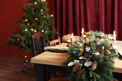 Photo of Dining table with burning candles and Christmas decor in stylish room. Interior design