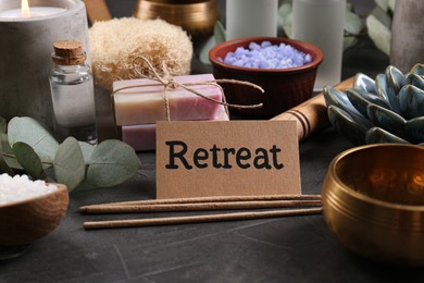 Card with word Retreat and different spa products on dark grey table