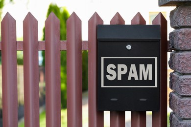 Mailbox with word Spam on fence outdoors. Space for text